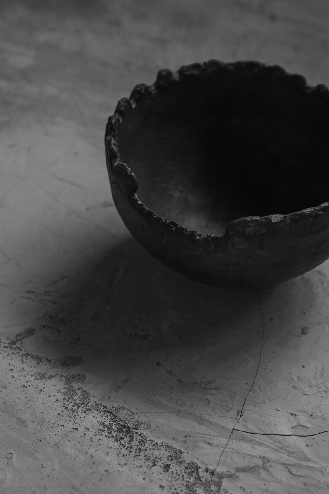 A hand-shaped black clay bowl with a raw rim
